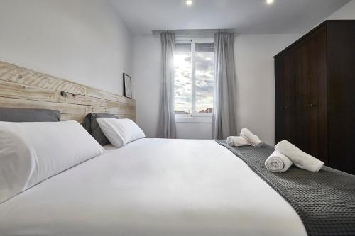 1 dormitorio con 1 cama blanca grande y toallas. en BBarcelona Fira Superior Flats en Barcelona