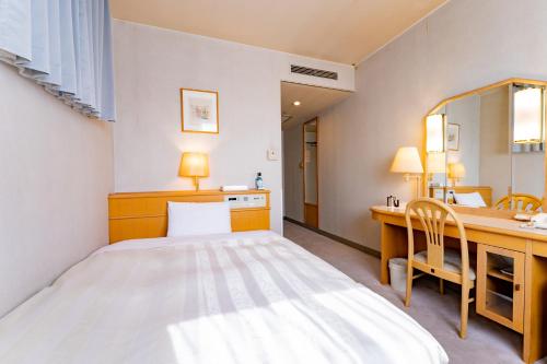 a bedroom with a bed and a desk and a mirror at Oyama Palace Hotel in Oyama