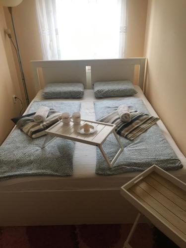 Una cama con una mesa y una ventana en Tudor Apartman, en Szeged