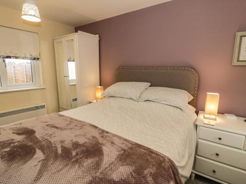 a bedroom with a bed with two lamps and a dresser at Can y Mor in Brynteg