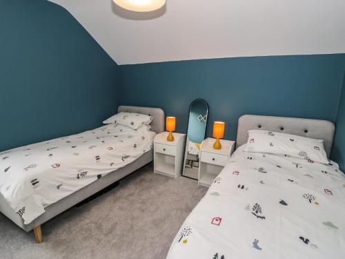 two beds in a room with blue walls at Can y Mor in Brynteg
