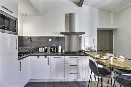 une cuisine avec des armoires blanches et une table avec des chaises dans l'établissement L'Exception, à Nîmes
