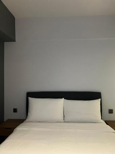 a white bed with a black headboard and white pillows at Doudian DDiNN Hotel in Taichung