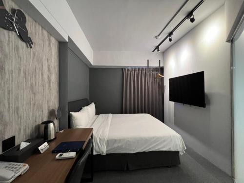 a bedroom with a bed and a desk and a television at Doudian DDiNN Hotel in Taichung