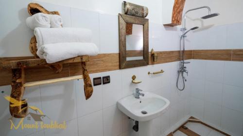 a bathroom with a sink and towels on a shelf at Mount Toubkal Lodge in Imlil