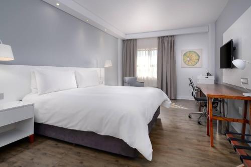 a hotel room with a large white bed and a desk at ANEW Hotel Roodepoort Johannesburg in Roodepoort