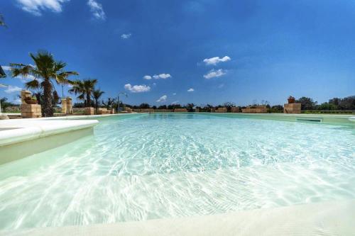 a large swimming pool with a blue sky and palm trees at Villa Salux by HDSalento in Taurisano