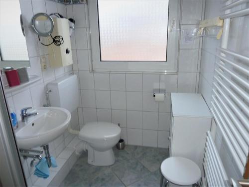 a white bathroom with a toilet and a sink at Kolks Huus Seglerweg in Neuharlingersiel