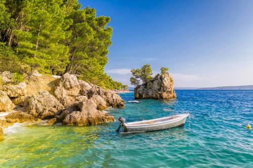 a boat in the water near a rocky island at Bluesun Hotel Maestral in Brela