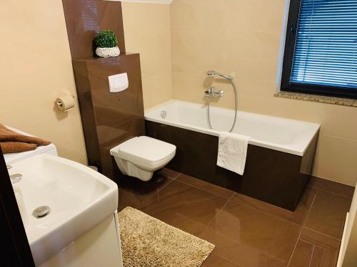 a bathroom with a tub and a toilet and a sink at Villa Kris in Pobierowo