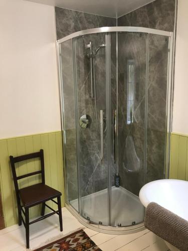 a shower in a bathroom with a chair and a tub at Rowan Cottage, CrannachCottages in Garve