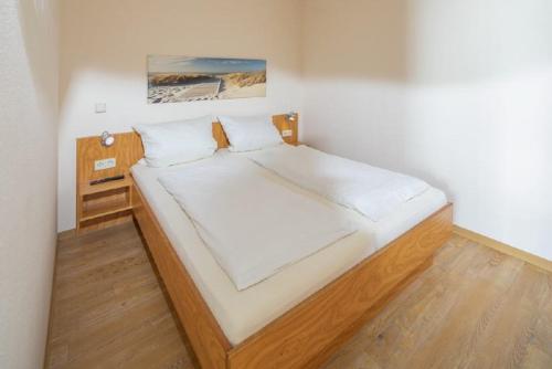 1 dormitorio con 1 cama grande con sábanas blancas en Ferienwohnung Kogge 4 en Norderney