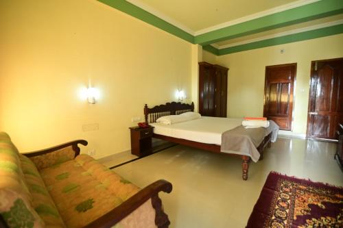 a bedroom with a bed and a couch in it at Sree Mookambika Beach Resort in Kovalam