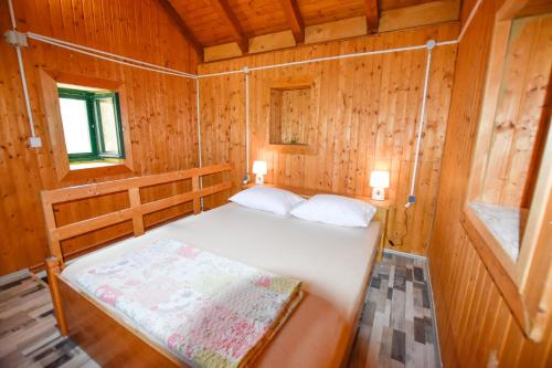a small room with a bed in a wooden cabin at House Pine Shadow in Pašman