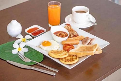 a plate of breakfast food on a table with a cup of coffee at Banyan Bay Villas in Ko Jum