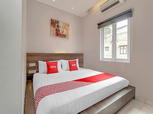 a bedroom with a large bed with red pillows at Super OYO Capital O 90726 The Regia Cihampelas Hotel in Bandung