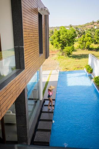 a woman with an umbrella standing next to a swimming pool at Luxury Goa Villa in Candolim