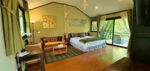 a bedroom with a bed and a couch in it at UTOPAI Stone Garden Vacation Home, Pai! in Ban Muang Soi