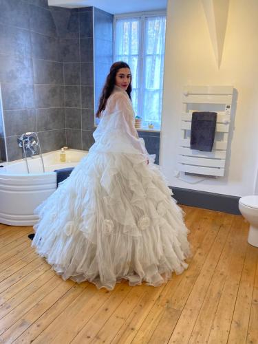 Uma rapariga com um vestido de noiva parada numa casa de banho em Gîte 6 personnes 3 chambres château de la bouchatte em Chazemais