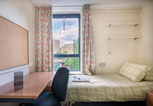 a bedroom with a desk and a bed and a window at LSE Rosebery Hall in London