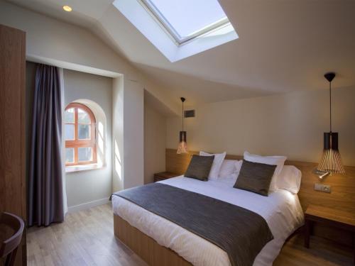 a bedroom with a large bed with a skylight at Apartaments Vall de Núria in Queralbs