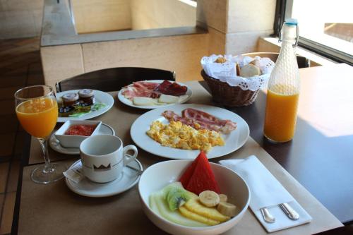 a table topped with plates of breakfast food and orange juice at Montemar in Llanes