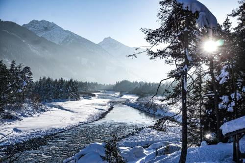 a river in the snow with mountains in the background at Pension & Ferienwohnungen Haus Edelweiß in Holzgau