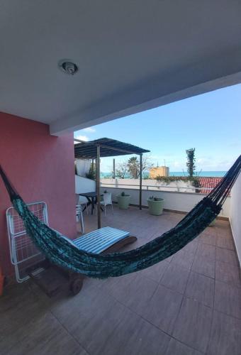 a hammock on top of a house with a patio at Village Hospedagens in Natal