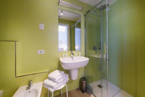 a green bathroom with a sink and a shower at Alessia' s Home in Tirano