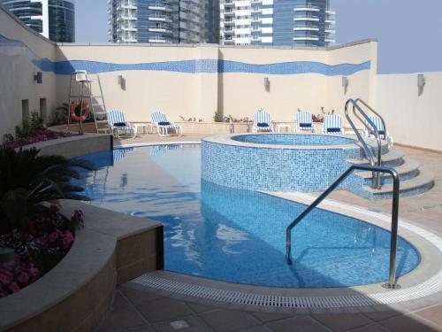 a large swimming pool with chairs in a building at Grand Bellevue Hotel Apartment Dubai in Dubai