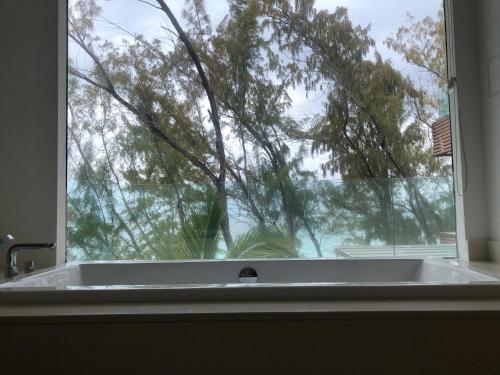 a bath tub in front of a window with a tree at Rose des Sables in Belle Mare