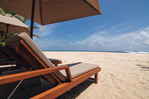 a chair and an umbrella on the beach at Three Gables Boutique Villa in Mirissa