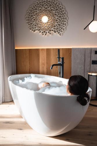 a woman is sitting in a white bath tub at BAD MOOS - Aqua Spa Resort in Sesto