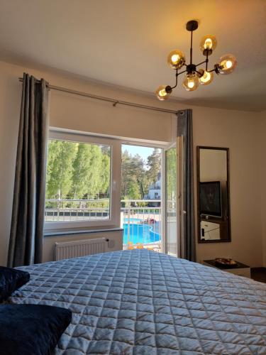 a bedroom with a large bed and a large window at Baltic Sun Apartament in Pobierowo
