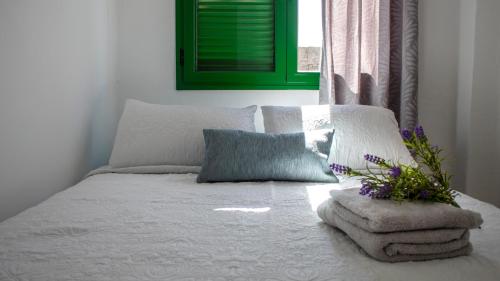 a white bed with a pillow and a bouquet of flowers on it at VILLA SEA&SKY - spectacular 180 degree ocean views in Puerto del Carmen