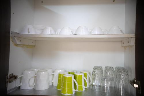a shelf filled with white and yellow mugs and glasses at ZaNaKri Homes ;A Great Panorama of Indian Ocean in Mombasa