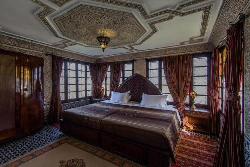 a bedroom with a bed with a coffered ceiling and windows at Riad Pacha Palace in Fès