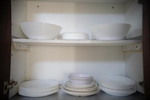 a group of white plates and bowls on a shelf at ZaNaKri Homes ;A Great Panorama of Indian Ocean in Mombasa