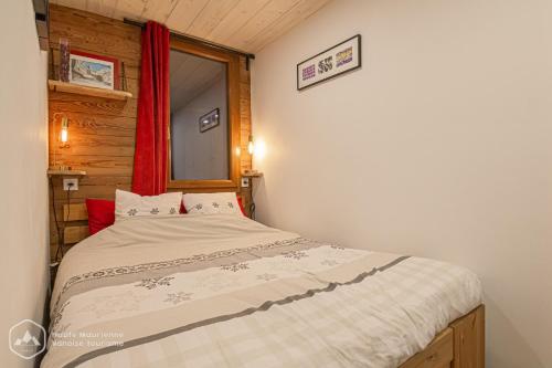 ein Schlafzimmer mit einem Bett und einem roten Vorhang in der Unterkunft Le Cocon de l'Arcelle in Lanslevillard