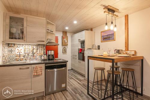 a kitchen with a counter and a bar with stools at Le Cocon de l'Arcelle in Lanslevillard