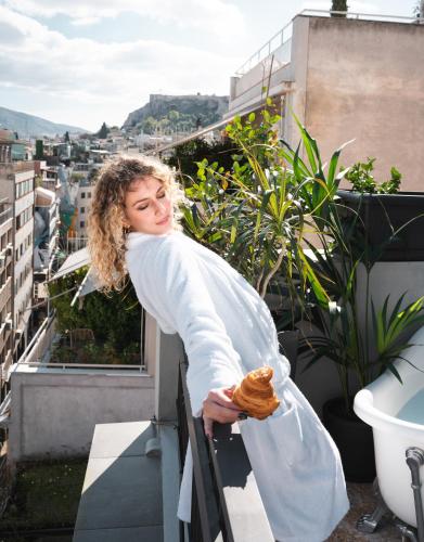a woman standing on a balcony with a pastry in her hand at PAME House in Athens