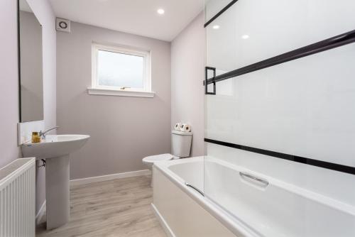 a white bathroom with a tub and a sink at The Orchard - Donnini Apartments in Ayr