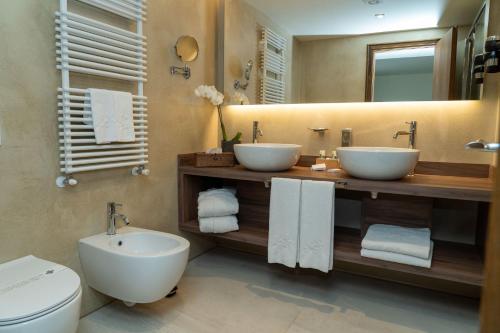 a bathroom with two sinks and a toilet and a mirror at Palace Hotel Wellness & Beauty in Bormio