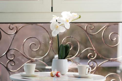 a table with two cups and a vase with white flowers at Rhome Hosting in Rome