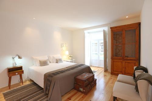 een witte slaapkamer met een bed en een stoel bij My Lisbon Apartment in Lissabon