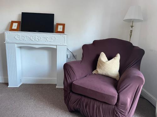 a purple chair sitting next to a table with a television at Modern Home just off Glastonbury High Street in Glastonbury
