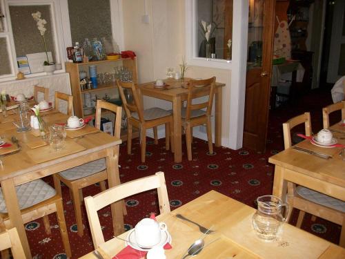 a dining room with wooden tables and chairs at Highbury Hotel in Blackpool