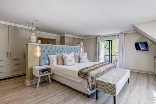 1 dormitorio con 1 cama grande y cabecero azul en Forest Edge Golf and Sea Villa, en Knysna