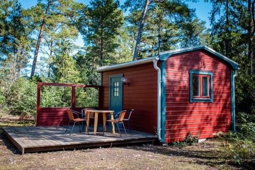 une cabine rouge avec une table et des chaises sur une terrasse dans l'établissement Lickershamns Semesterby, à Lickershamn