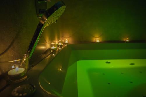 a bathroom with a green tub with candles and lights at Lemmas Apartament Anchoria in Mechelinki